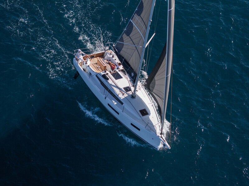 Sun Odyssey 350 purjeiden ollessa täysin ylhäällä, navigoimassa kirkkaan taivaan alla.