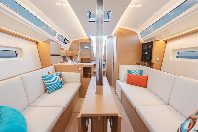 Ruokailutila Sun Odyssey 350:ssä, jossa moderni pöytä ja pehmustetut istuimet.