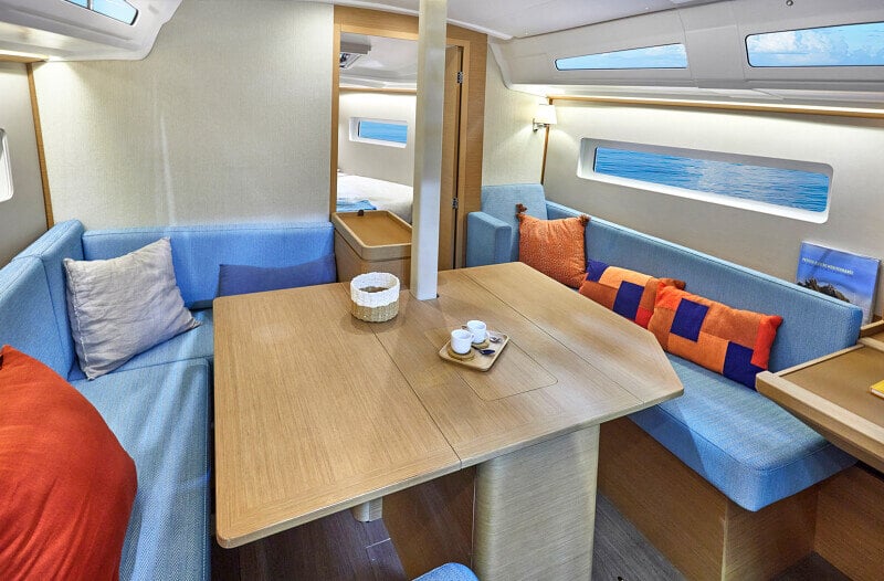 Ruokailutila Sun Odyssey 380:ssä, jossa tilava pöytä ja pehmustetut istuimet perheille ja ystäville.