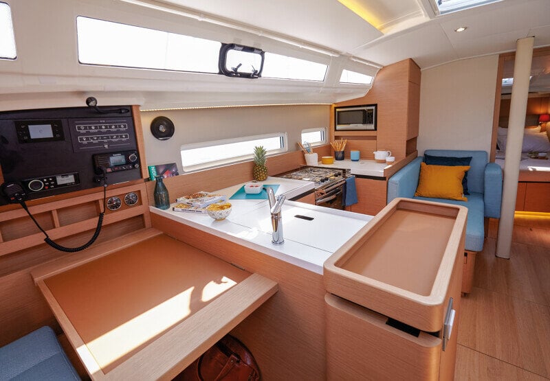 Sun Odyssey 410 keittiö käytössä – Veneilijä valmistamassa ruokaa hyvin varustellussa keittiössä.