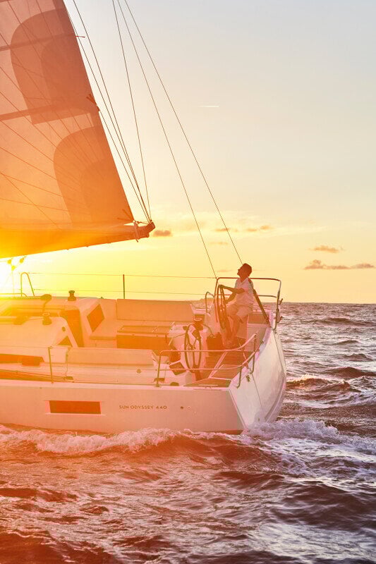 Sun Odyssey 440 auringonlaskun valossa, heijastuen kauniisti vedestä.
