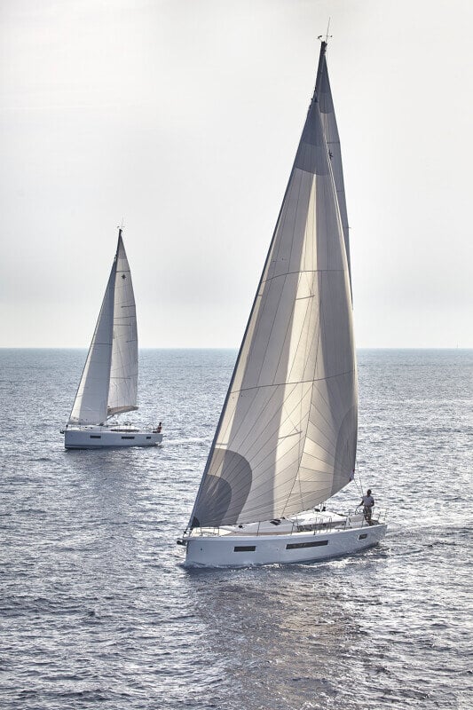 Sun Odyssey 490 - kaksi Jeanneau-purjevenettä rinnakkain avomerellä, elegantti ja moderni muotoilu.