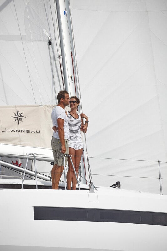 Sun Odyssey 490 - pariskunta rentoutuu kannella Jeanneau-logon edessä