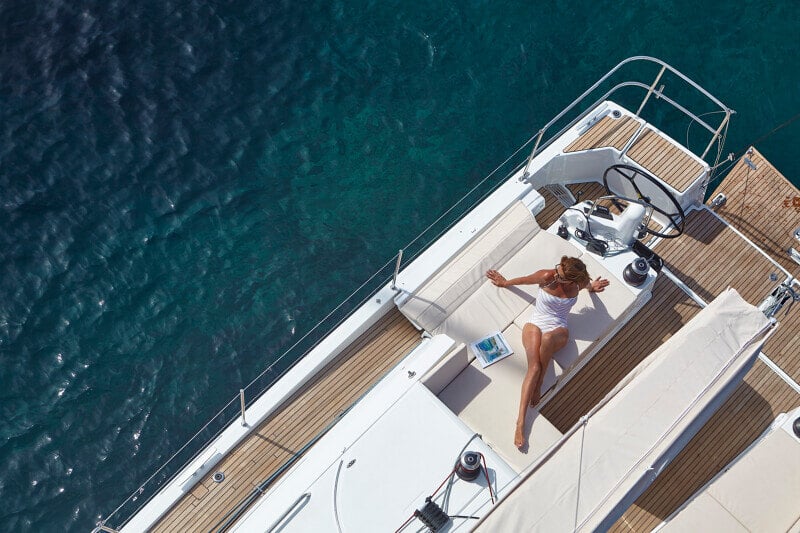 Sun Odyssey 490 - kaunis purjevene auringonpaisteessa, matkustajat nauttimassa rennosta merimatkasta.
