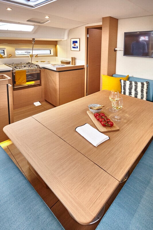 Sun Odyssey 490 - ruokailutila: Elegantti ruokailutila, jossa viinilasi ja herkullinen alkupala aseteltuna pöydälle.