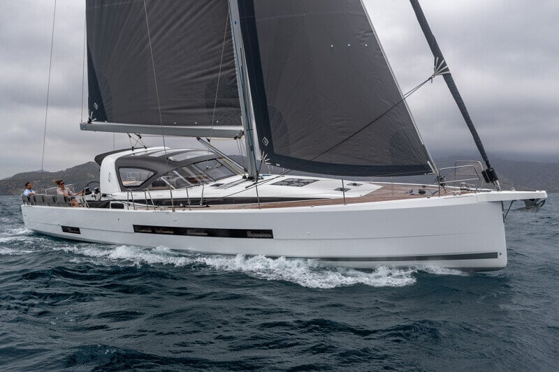 Jeanneau Yachts 55 risteilee avomerellä tyylikkäänä ja suorituskykyisenä purjeveneenä, taustalla upea merimaisema.
