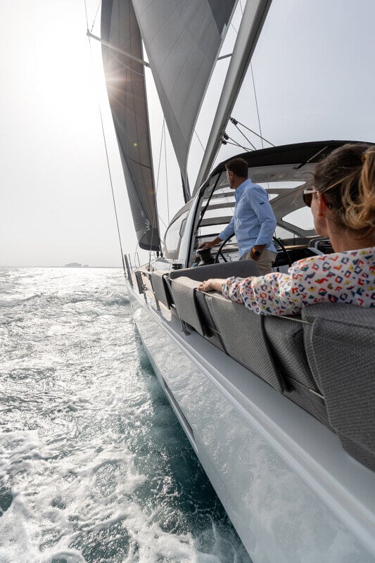 Jeanneau Yachts 55 purjehtimassa rauhallisilla vesillä, taustalla jylhät kalliorannat ja sininen meri.