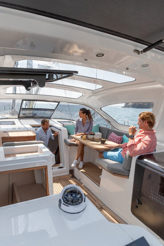 Pariskunta valmistautuu nauttimaan aamukahvista Jeanneau Yachts 55:n katetussa lounge-tilassa, jossa merinäköala korostuu.