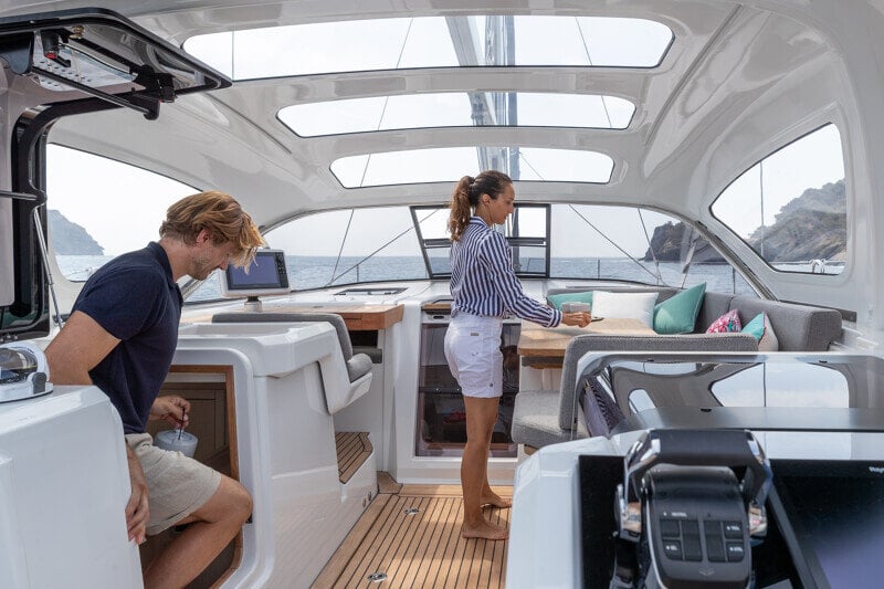 Nainen lepää Jeanneau Yachts 55:n katetussa lounge-tilassa, jossa suuret ikkunat tarjoavat upean merinäköalan.