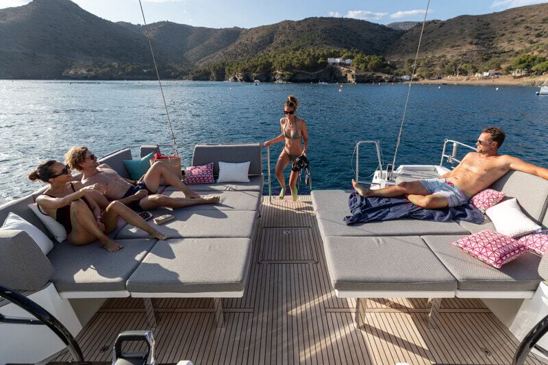 Jeanneau Yachts 55 ankkurissa, matkustajat nauttivat merestä ja auringosta kannen lounge-tiloissa.
