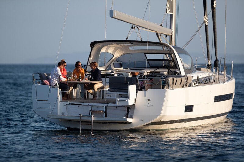Peräkannelta kuvattu Jeanneau Yachts 55, jossa matkustajat valmistautuvat sukeltamaan kristallinkirkkaaseen mereen.