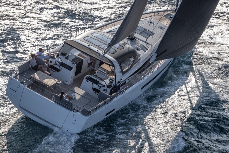 Takakulmasta kuvattu Jeanneau Yachts 55 purjehdusmatkalla, jossa miehistö nauttii kannen mukavista oleskelutiloista.