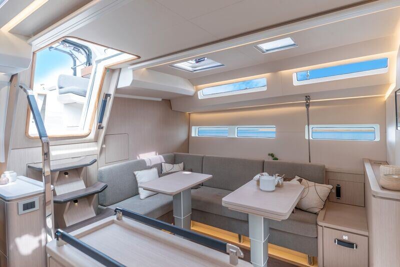 Jeanneau Yachts 55:n valoisa ja kodikas oleskelutila, jossa on mukavat sohvat, pehmeät tyynyt ja avarat näkymät ulos.