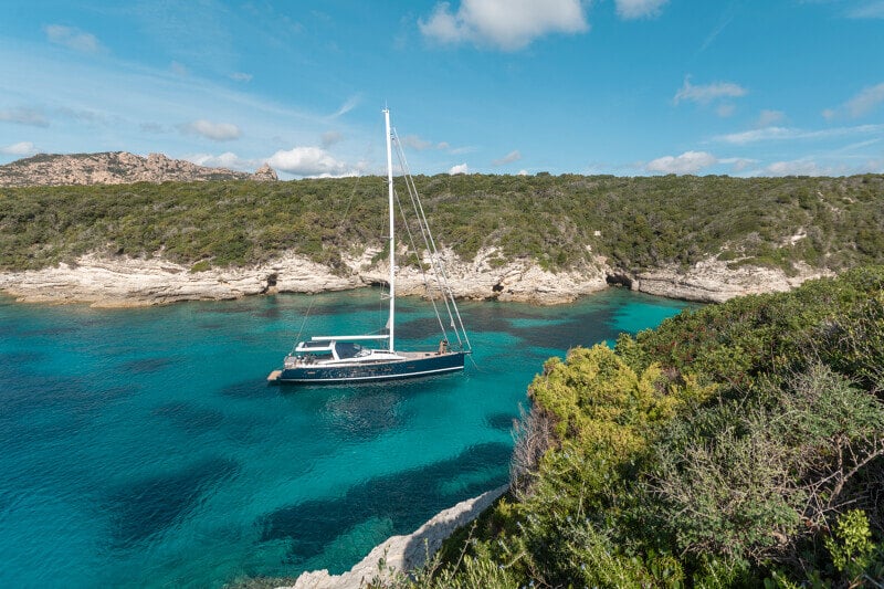 Jeanneau Yachts 65 ankkurissa rauhallisessa lahdessa, heijastus vedessä.
