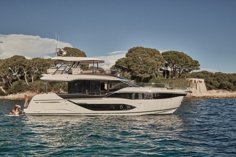 Luxury Prestige F5.7 yacht anchored near an exclusive beach resort.